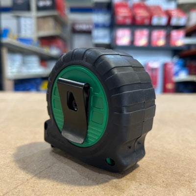 The rear side of a green Tape Measure with a belt hook and rubber casing