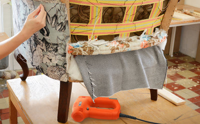 young female upholsterer using the new electric Tacwise 140 Series stapler to re-upholster the rear of classic seat.